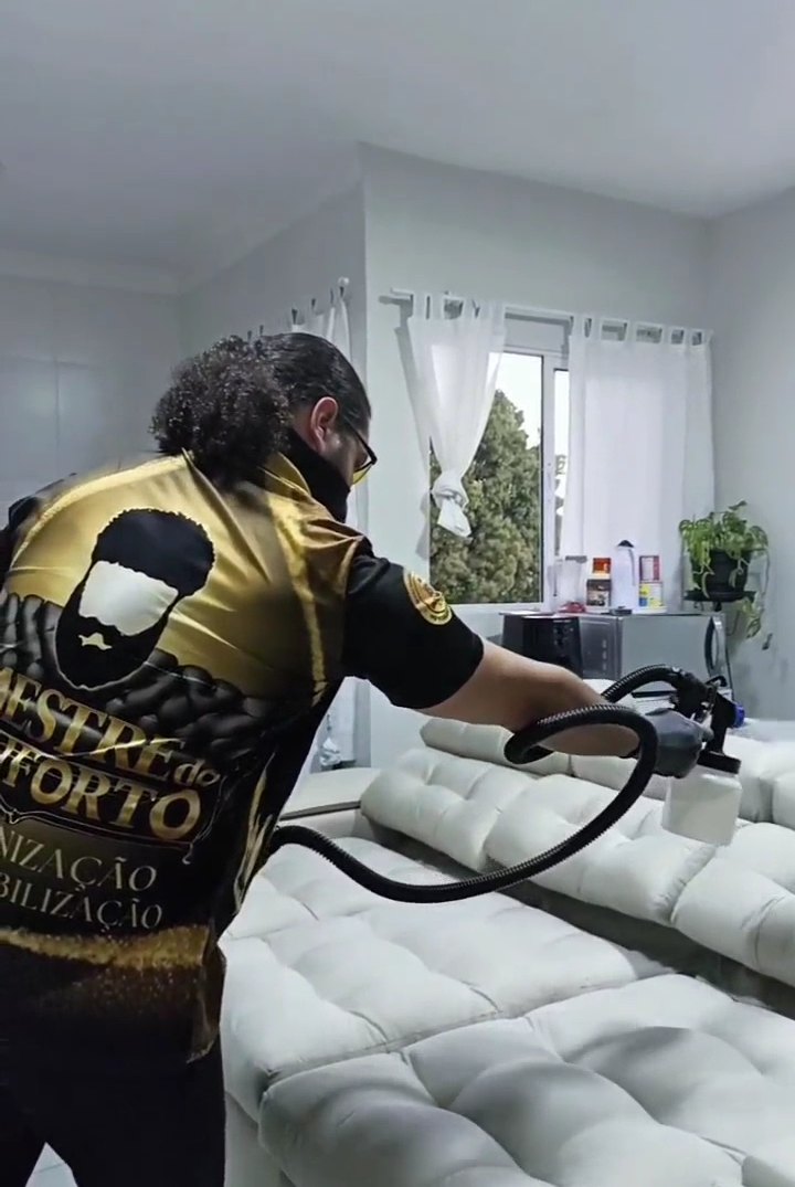 Técnico uniformizado da Herbo Clean higienizando um sofá na casa do cliente